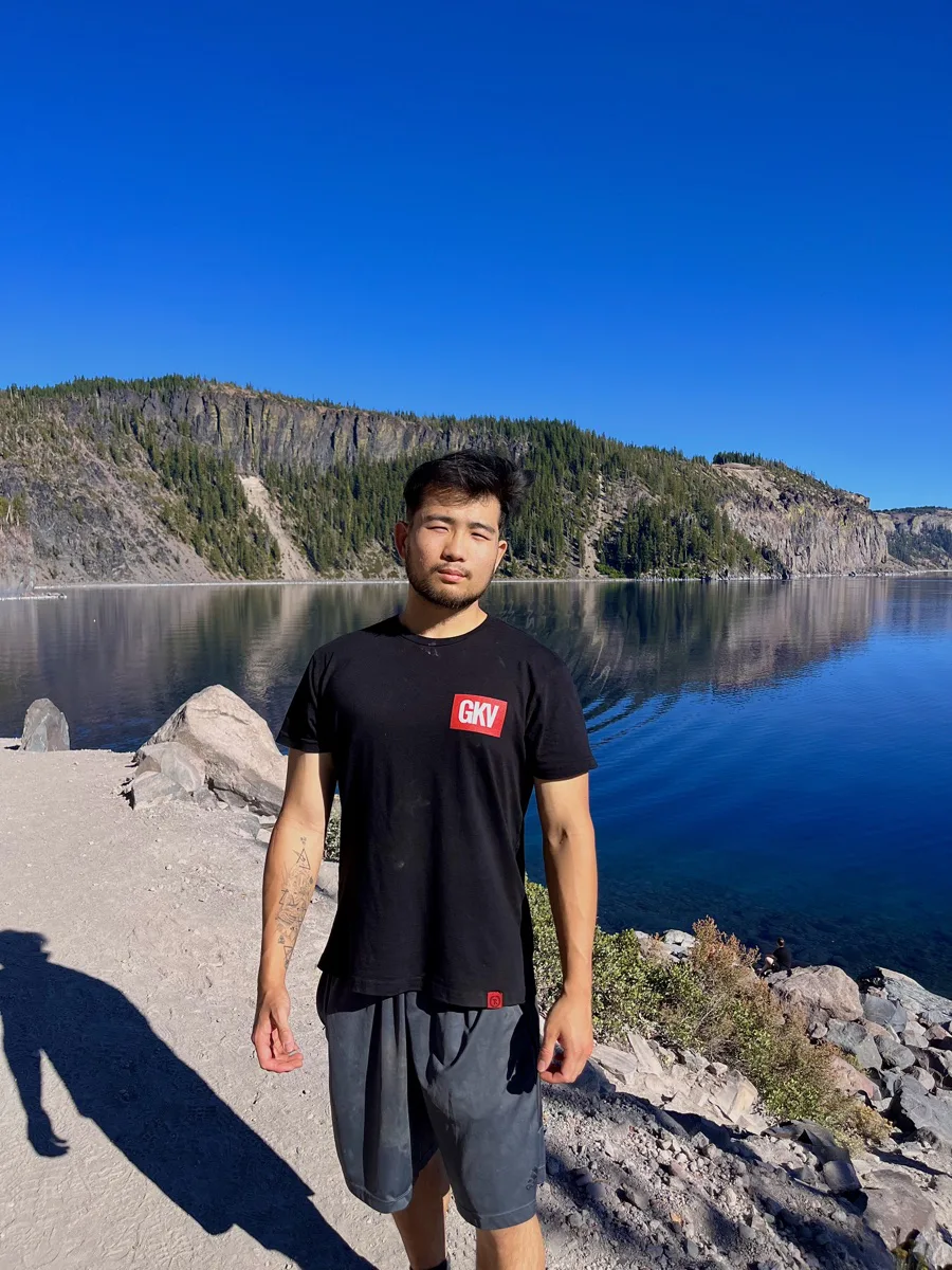 Steven Yang standing beside a mountain lake